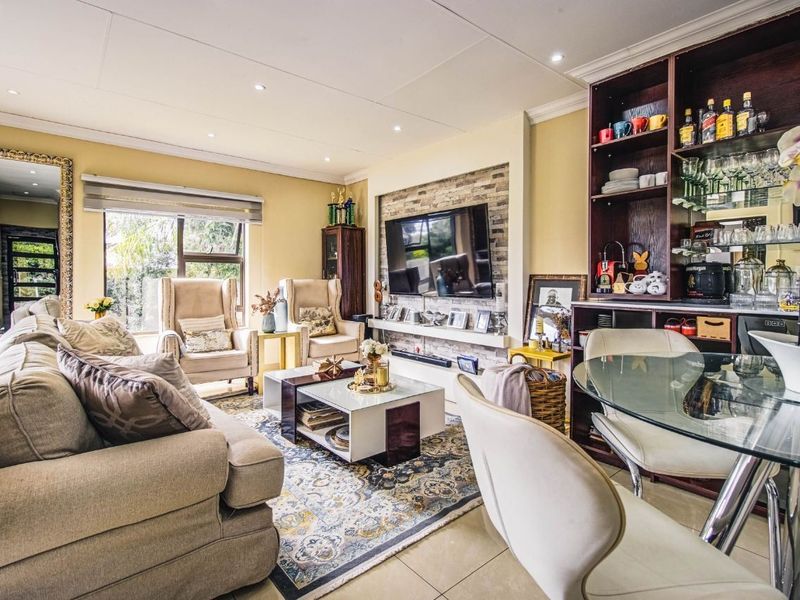 Spacious living room featuring a stone-clad feature wall, built-in shelving, recessed lighting, and tiled flooring, creating a comfortable and well-defined entertainment space.