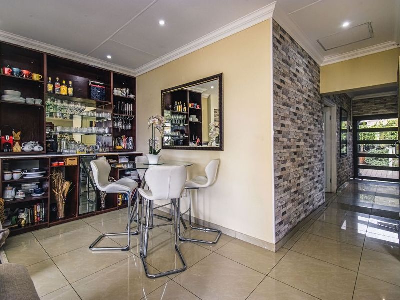 A well-appointed home bar area featuring custom built-in cabinetry, a decorative stone veneer feature wall, and polished tile flooring.