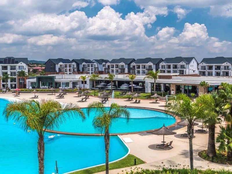 A wide-angle view of a large communal swimming pool area surrounded by modern apartment buildings and landscaped grounds.