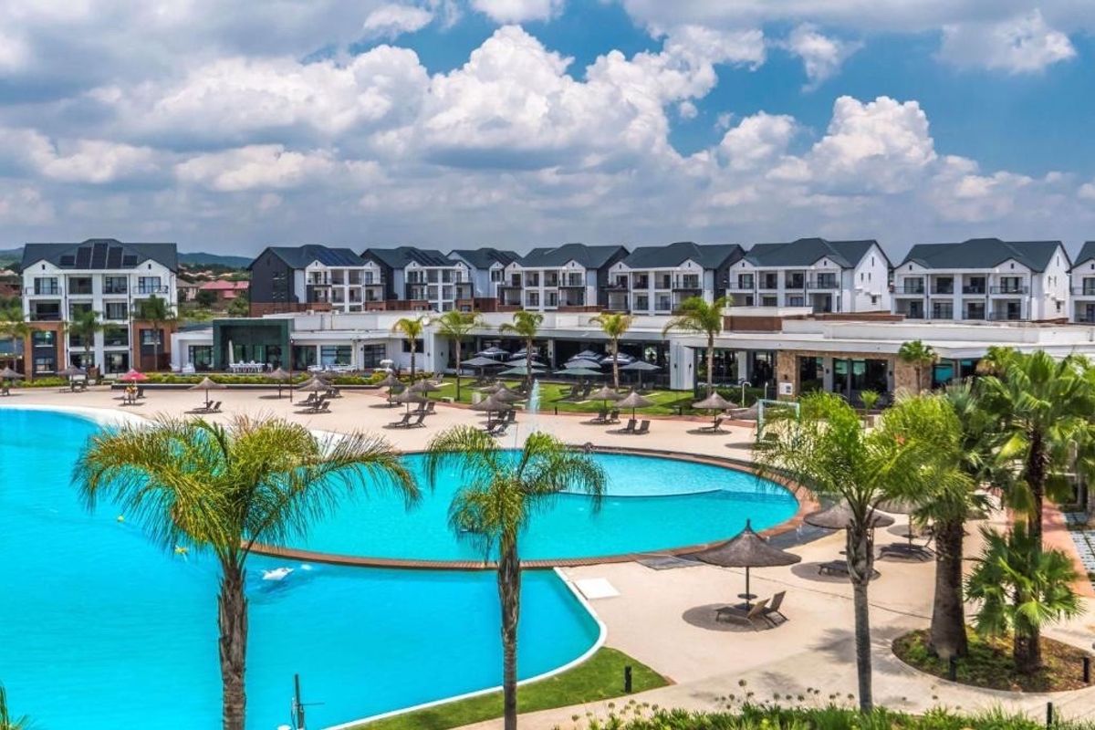 A wide-angle view of a large communal swimming pool area surrounded by modern apartment buildings and landscaped grounds.