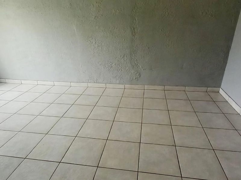 An empty bedroom featuring neutral tiled flooring and painted walls, providing a blank canvas for personalization and interior design updates.