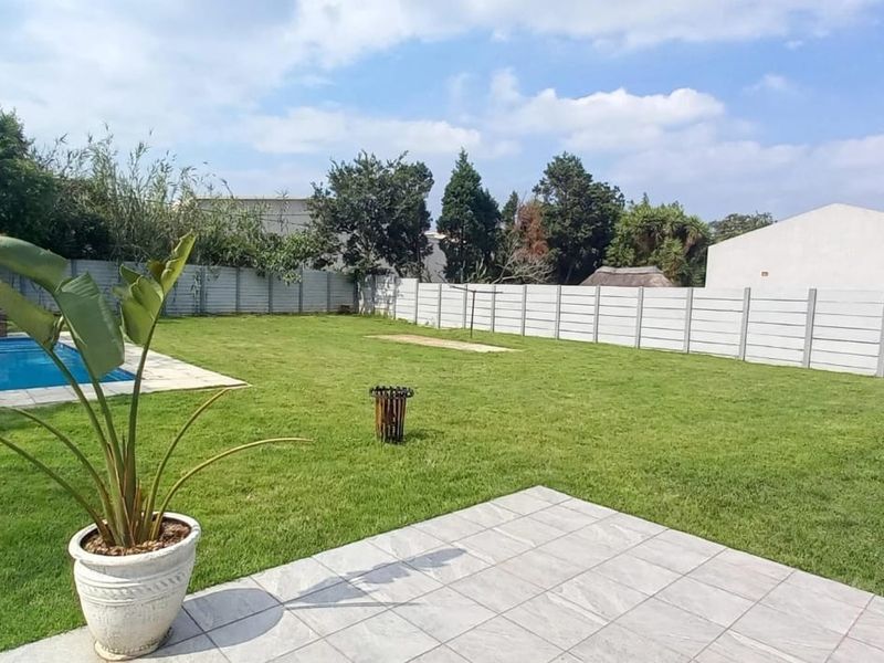 Spacious rear garden featuring a swimming pool, tiled patio area, and secure precast concrete boundary walling.