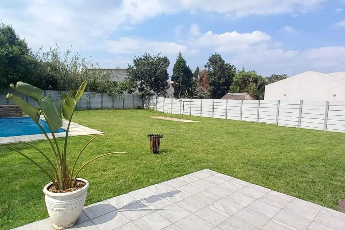 Spacious rear garden featuring a swimming pool, tiled patio area, and secure precast concrete boundary walling.