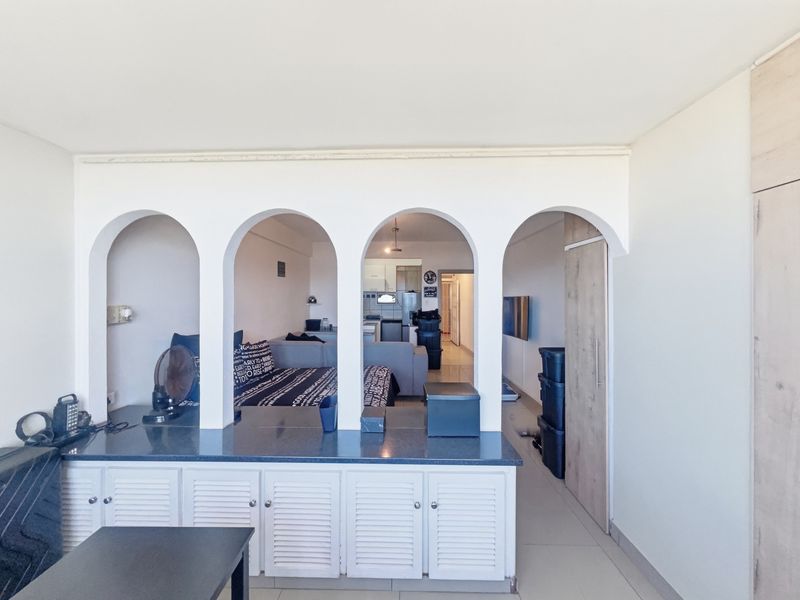 Open plan living area featuring a distinctive arched room divider with built-in cabinetry and stone countertop, connecting to the kitchen and living space.