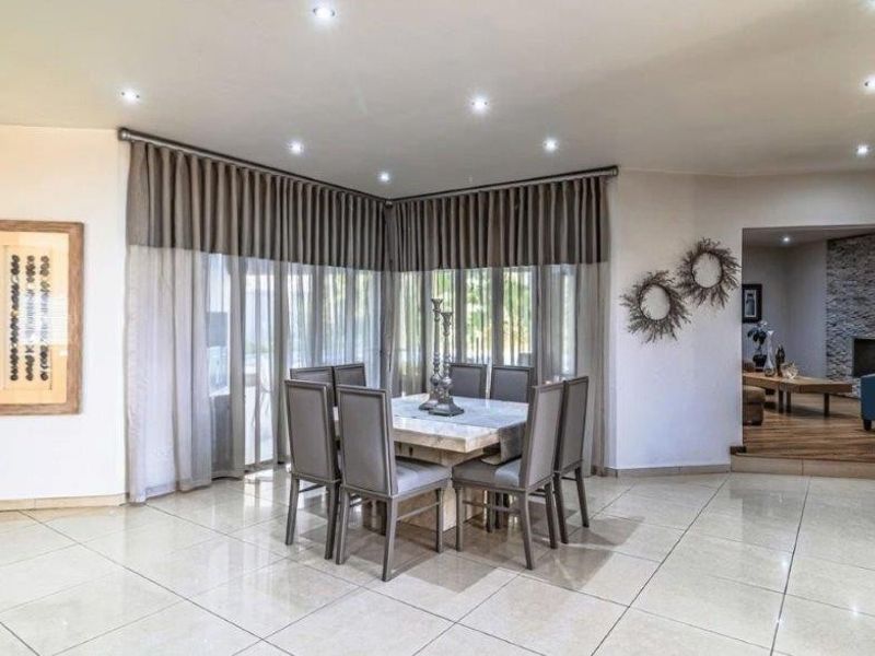 Spacious dining area featuring large format floor tiles, recessed downlighting, and expansive windows with integrated curtain tracks, offering a bright and open atmosphere.
