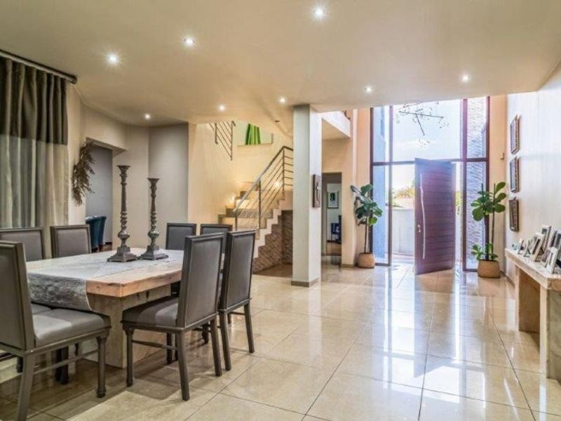 Spacious double-volume entrance hall featuring tiled flooring, recessed lighting, and an elegant staircase, creating an inviting and open atmosphere.
