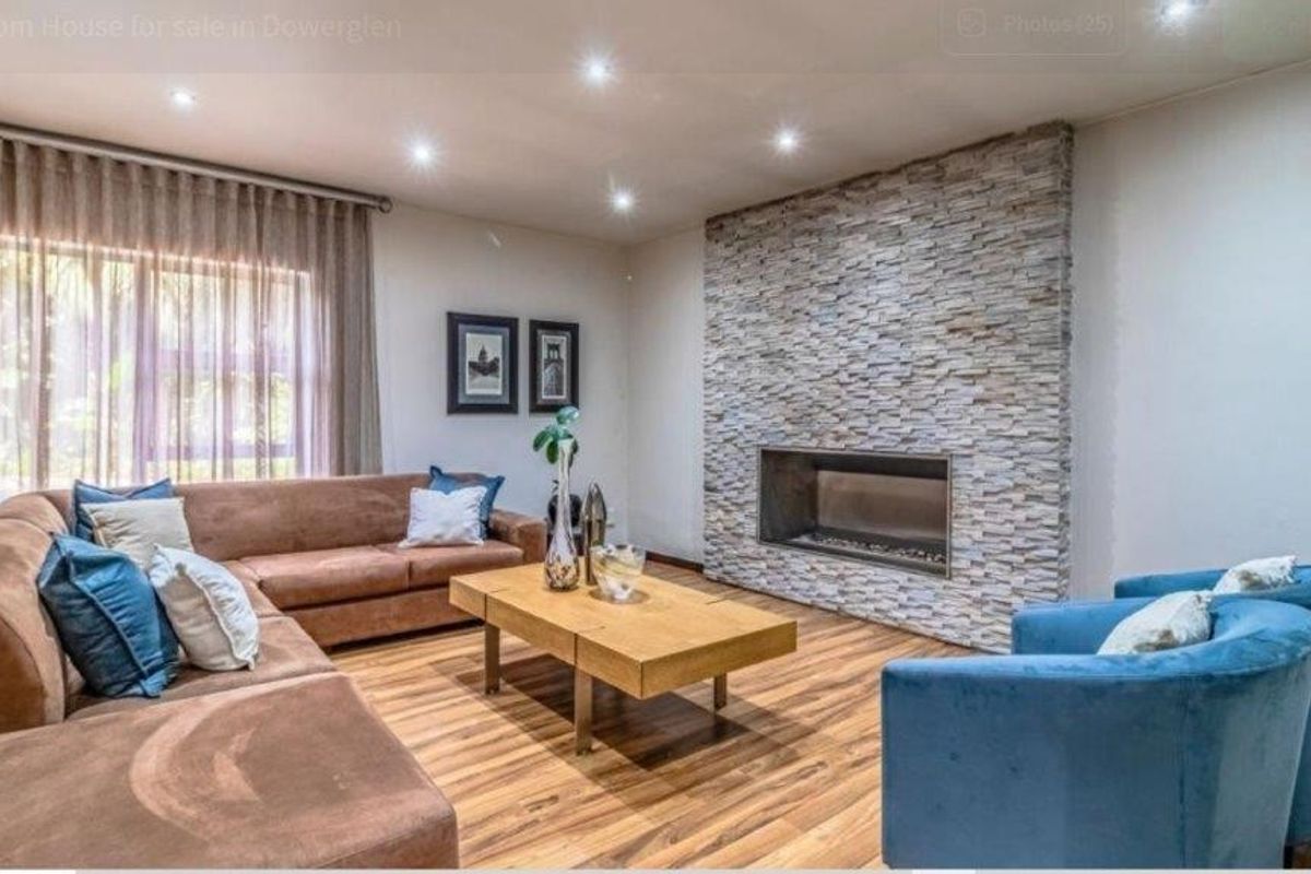 Spacious living room featuring a modern stone-clad fireplace, recessed downlighting, and warm-toned laminate flooring.
