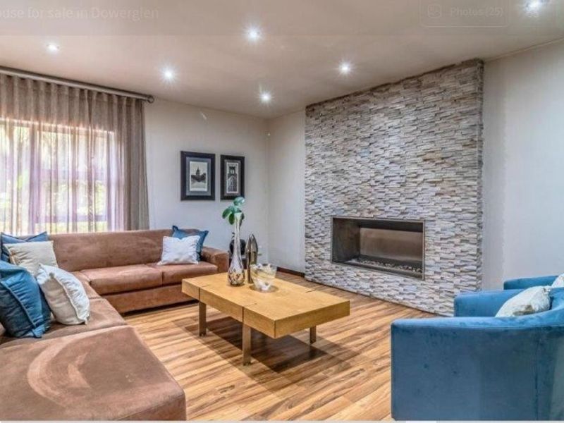 Spacious living room featuring a modern stone-clad fireplace, recessed downlighting, and warm-toned laminate flooring.