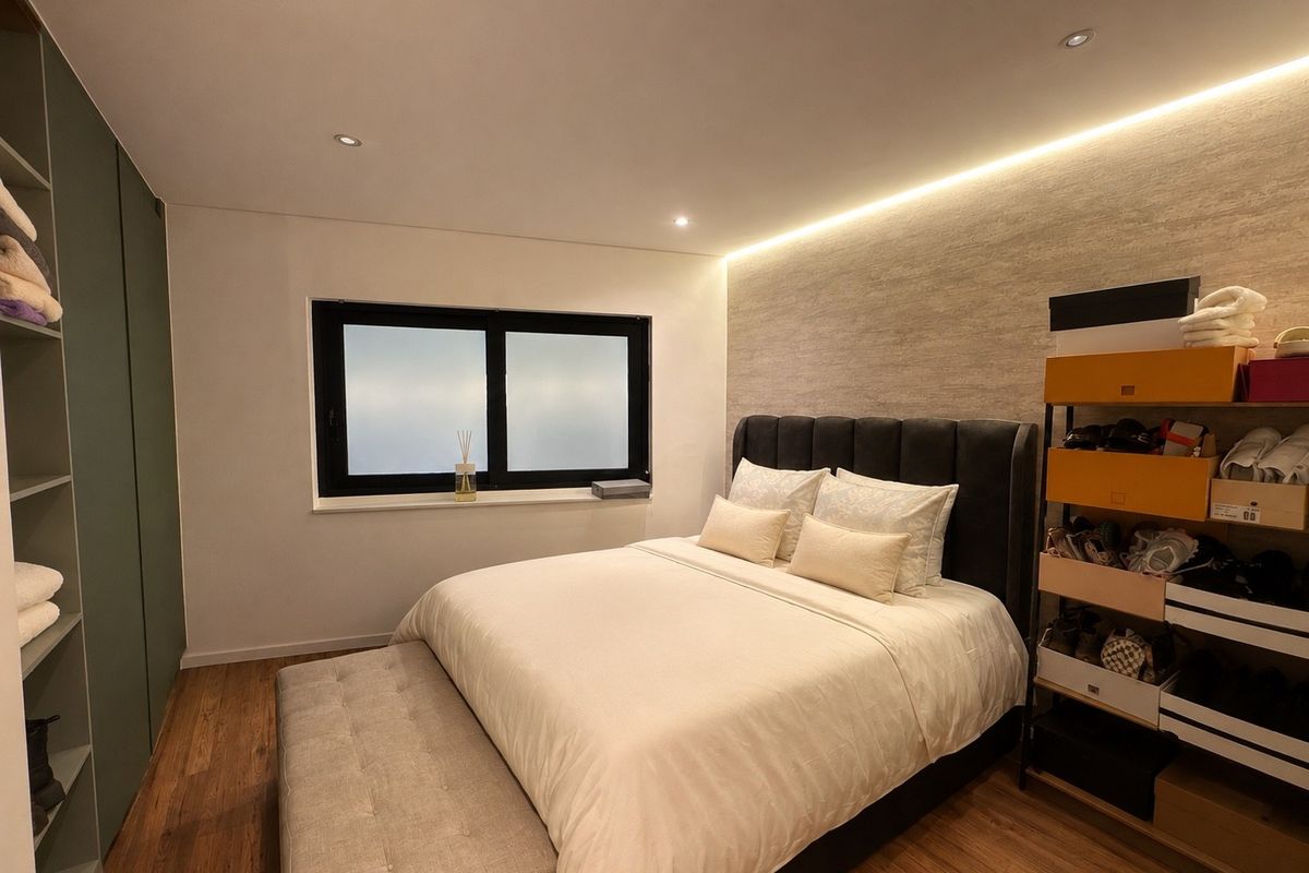 A modern bedroom featuring built-in wardrobes, warm LED accent lighting, recessed ceiling lights, and high-quality laminate flooring.