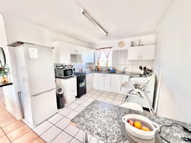A functional kitchen featuring white cabinetry, laminate countertops, tiled backsplash, and ceramic flooring, providing a practical workspace for daily meal preparation.