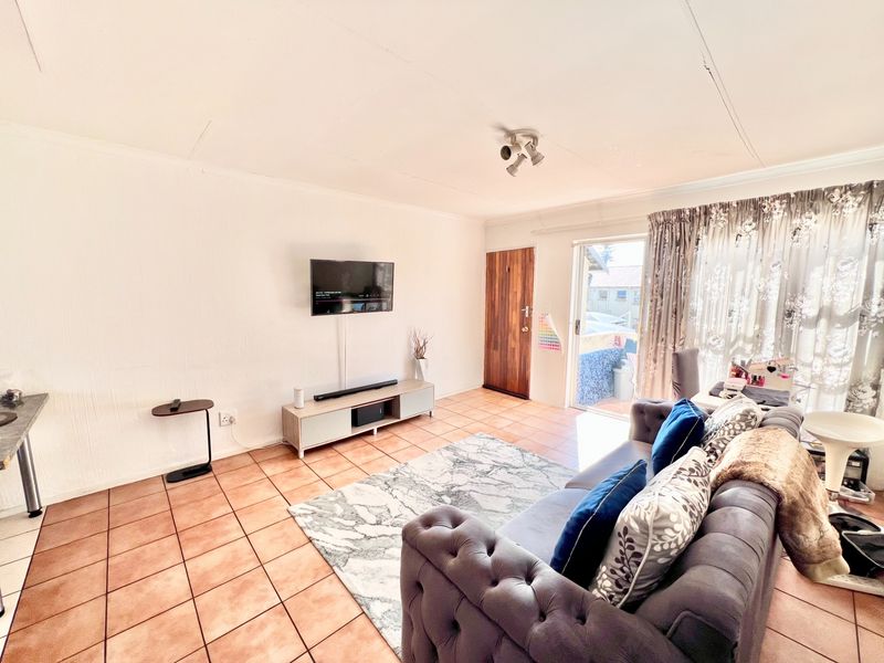A living room featuring tiled flooring, a sliding glass door providing outdoor access, and a timber entrance door.