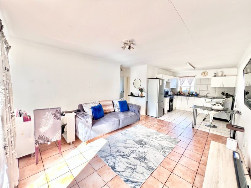 Open-plan living and kitchen area featuring tiled flooring and functional built-in cabinetry, offering a versatile space for daily living and dining.