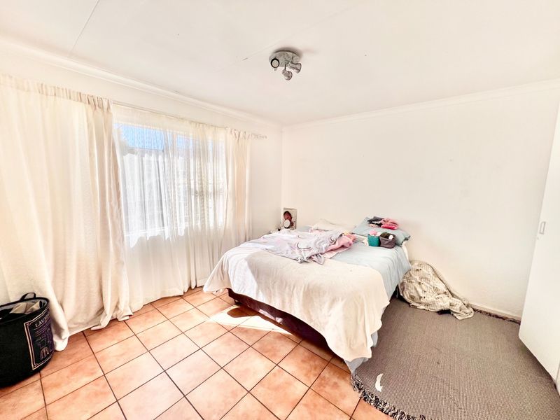 A bedroom featuring ceramic tile flooring and a central ceiling light fixture, offering a functional space with natural light from the window.