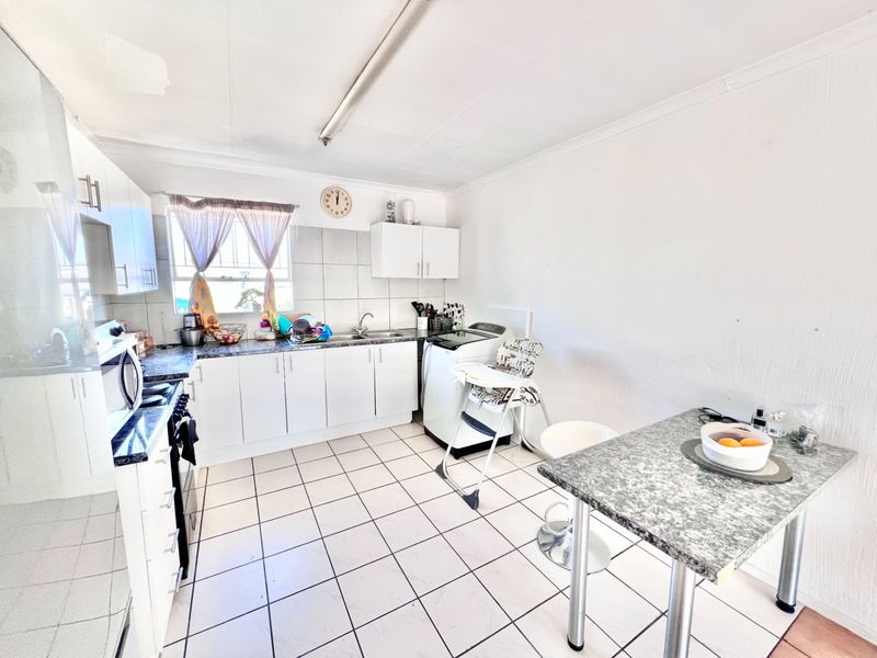 Functional kitchen featuring white cabinetry, laminate countertops, tiled flooring, and a built-in oven, offering a practical layout for daily meal preparation.