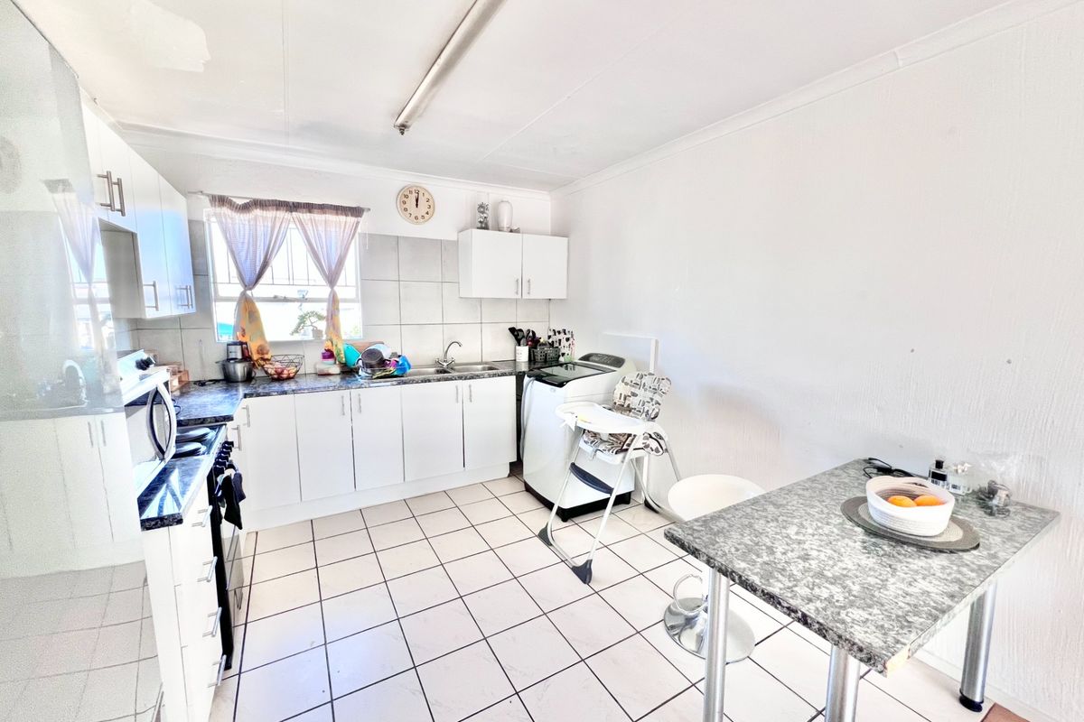 Functional kitchen featuring white cabinetry, laminate countertops, tiled flooring, and a built-in oven, offering a practical layout for daily meal preparation.