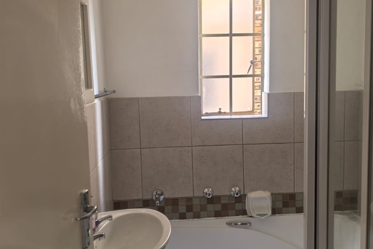 A functional bathroom featuring a pedestal basin, a built-in bathtub with tiled splashback, and a separate shower enclosure.