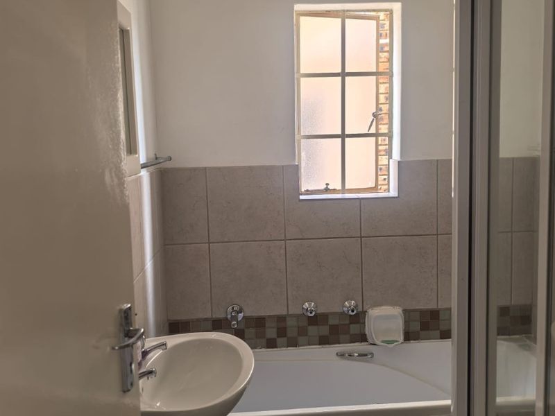 A functional bathroom featuring a pedestal basin, a built-in bathtub with tiled splashback, and a separate shower enclosure.
