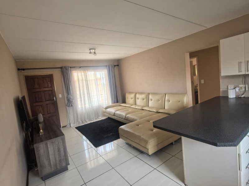 Open plan living area featuring tiled flooring, a kitchen breakfast bar with cabinetry, and direct access to the entrance.