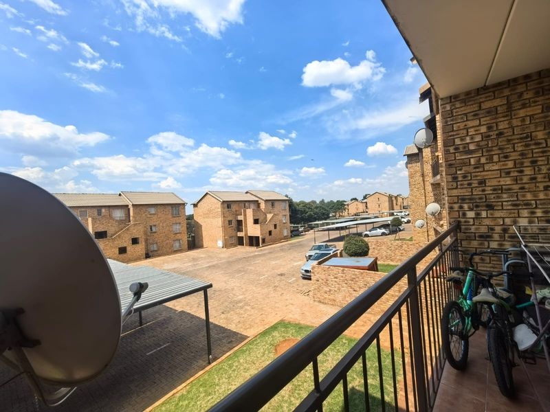 A balcony view overlooking the townhouse complex parking area and surrounding residential buildings.