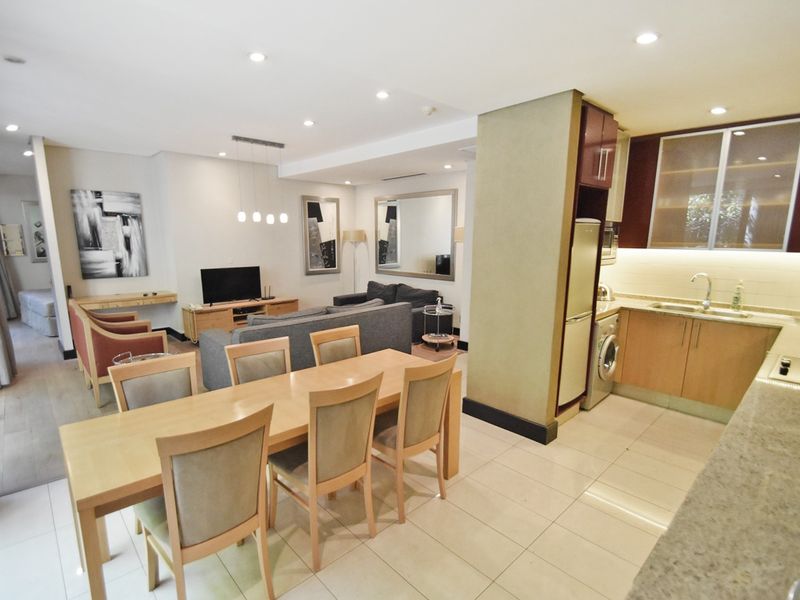 Spacious open-plan living area featuring a modern kitchen with stone countertops, integrated appliances, and tiled flooring throughout the dining and lounge space.