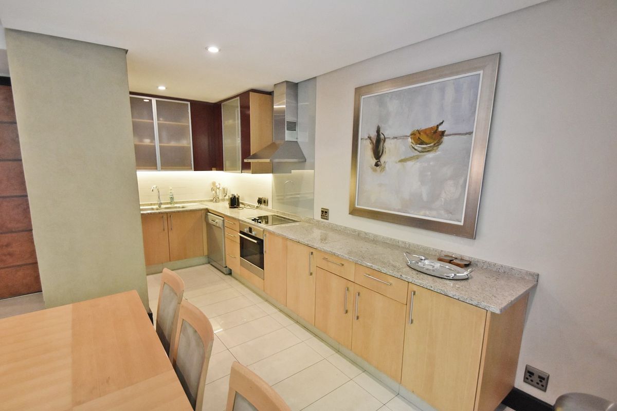 Modern kitchen featuring light wood cabinetry, granite countertops, integrated stainless steel appliances, and tiled flooring with recessed lighting.