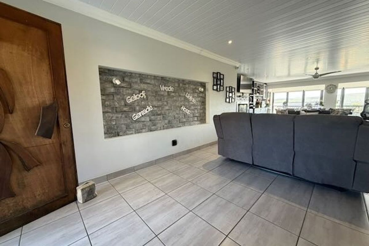 Spacious living area featuring a unique recessed stone feature wall, tiled flooring, and a modern tongue and groove ceiling with integrated lighting.