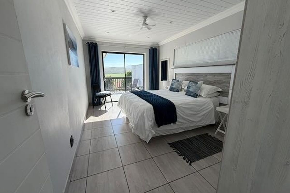 A bright bedroom featuring tiled floors, a tongue and groove ceiling with a fan, and sliding glass doors leading to a private balcony.