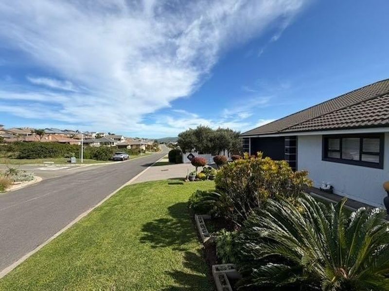 A clear street-level view of the property exterior, showcasing the driveway, landscaped front garden, and residential neighborhood setting.