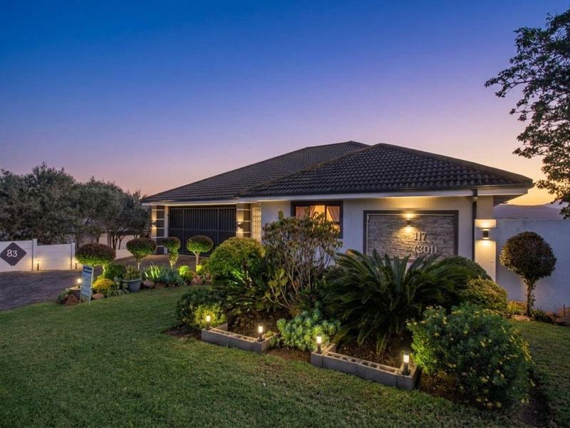 Attractive front elevation of a well-maintained house featuring a tiled roof, double garage, stone cladding detail, and manicured garden with integrated lighting.