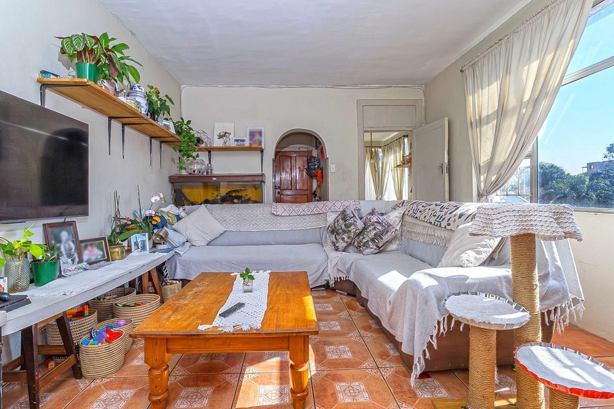 A living room featuring tiled flooring, an arched doorway, and natural light from a large window.