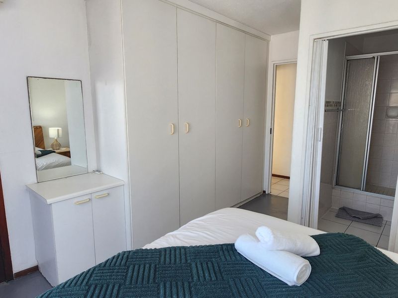 Bedroom featuring built-in cupboards, an en-suite bathroom with a shower cubicle, and an integrated air conditioning unit.