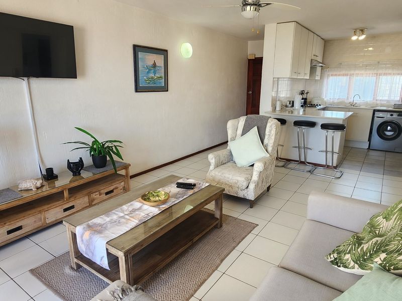 Open-plan living area featuring a functional kitchen with island, tiled flooring, and integrated laundry space, creating a cohesive and practical living environment.