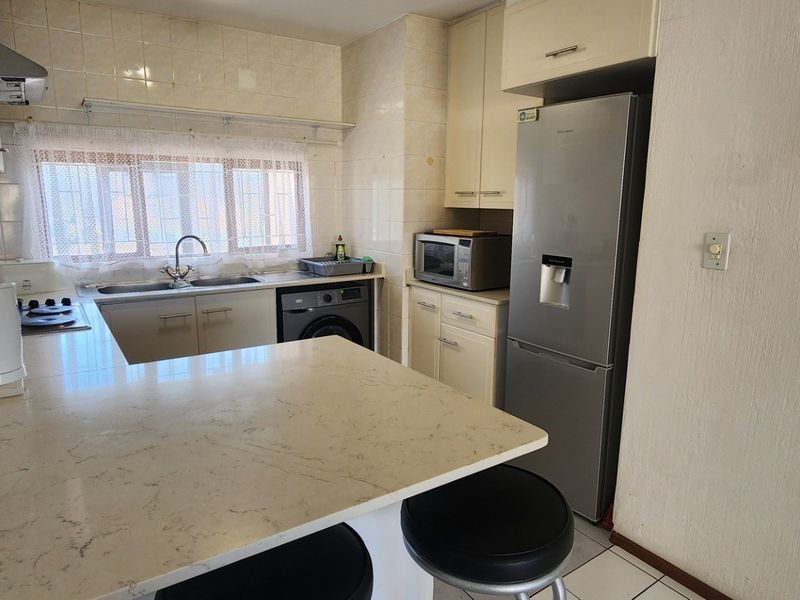 A functional kitchen featuring built-in cabinetry, stone countertops, a tiled backsplash, and integrated cooking appliances, offering a practical layout for daily use.