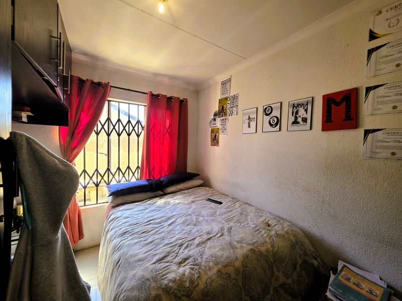 A compact bedroom featuring built-in cabinetry, a security gate on the window, and standard ceiling finishes.