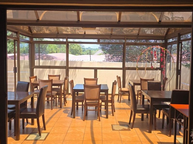 Enclosed patio area featuring tiled flooring, aluminum framing, and a translucent roof, providing a bright and versatile space for dining or relaxation.