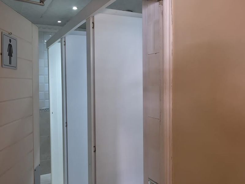 A functional communal bathroom area featuring partitioned toilet cubicles and recessed ceiling lighting.