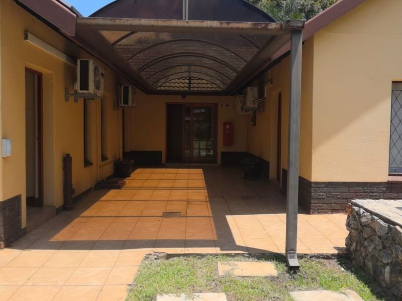 A covered outdoor patio area featuring tiled flooring, wall-mounted air conditioning units, and a stone retaining wall, providing a functional transition space.