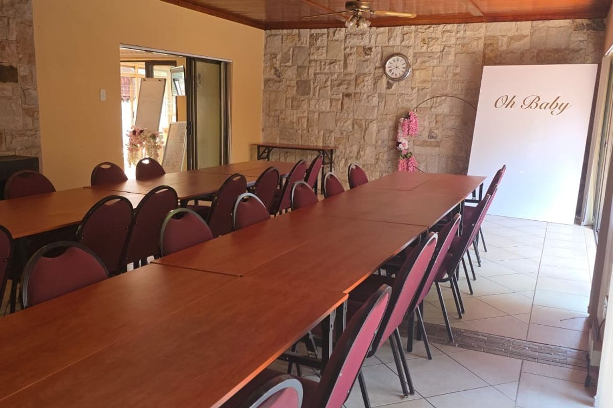 A spacious function room featuring stone-clad feature walls, tiled flooring, and large sliding glass doors providing natural light.