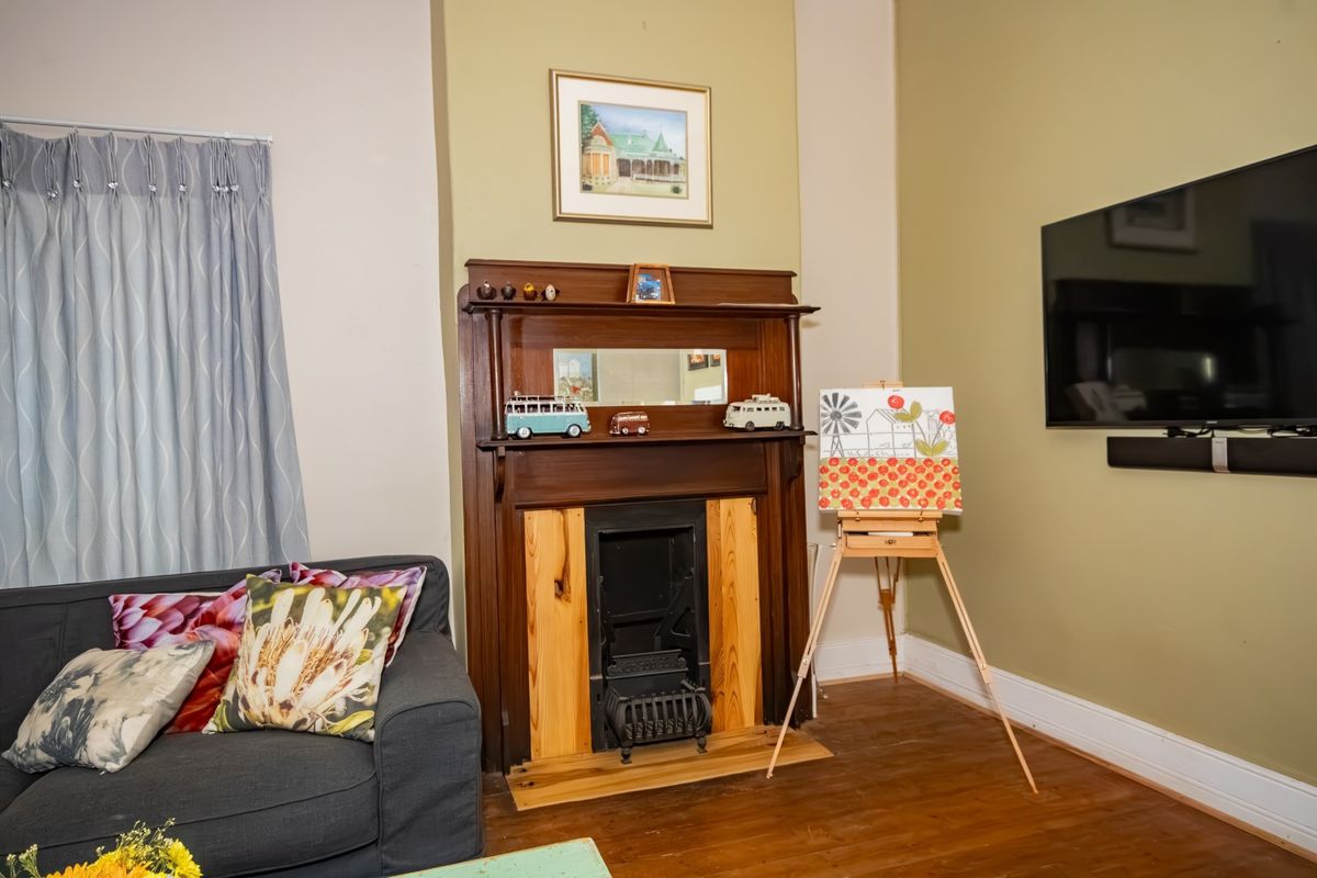 Living room featuring a traditional timber fireplace mantel with a cast iron insert and polished timber flooring.