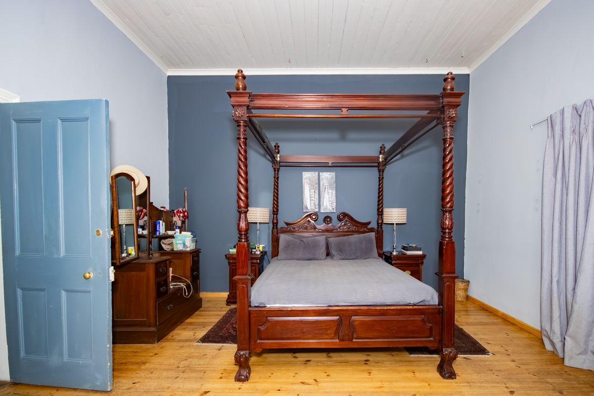 A spacious bedroom featuring polished timber flooring and a classic tongue and groove ceiling, providing a solid foundation for interior updates.