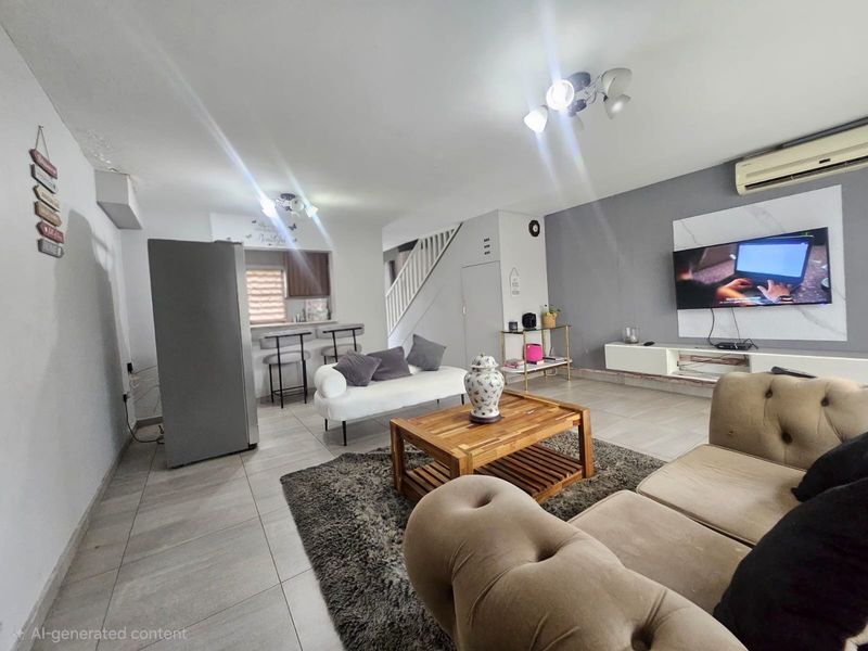 Open-plan living area featuring tiled floors, a breakfast bar, staircase, and wall-mounted air conditioning unit.