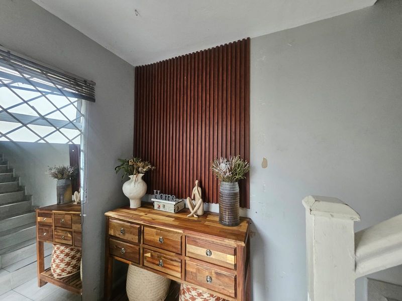 A hallway area featuring a decorative timber slat wall panel and staircase access, showing signs of wear on the wall finish.
