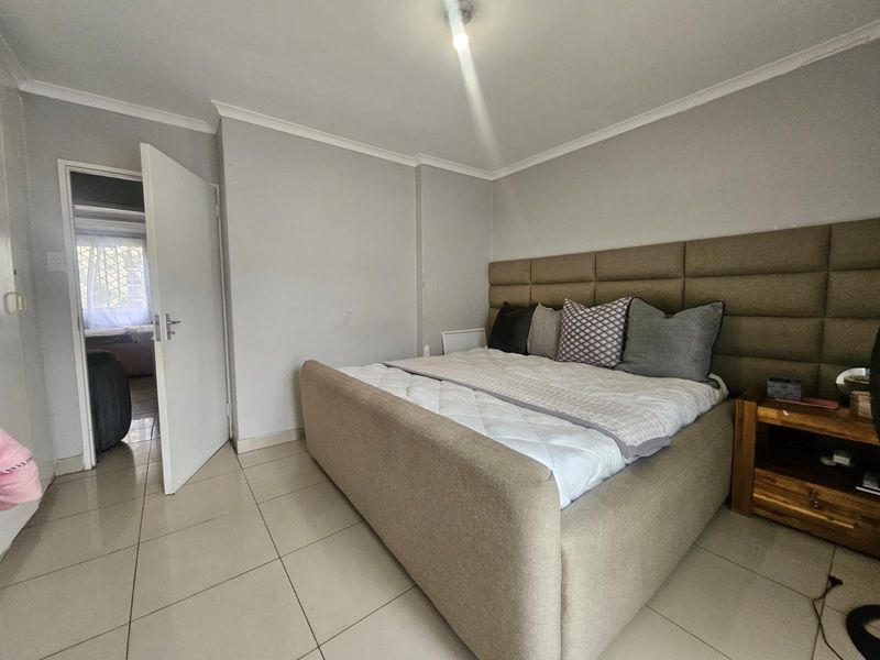 A bedroom featuring neutral wall tones, tiled flooring, and a coved ceiling, with an open doorway leading to an adjacent room.