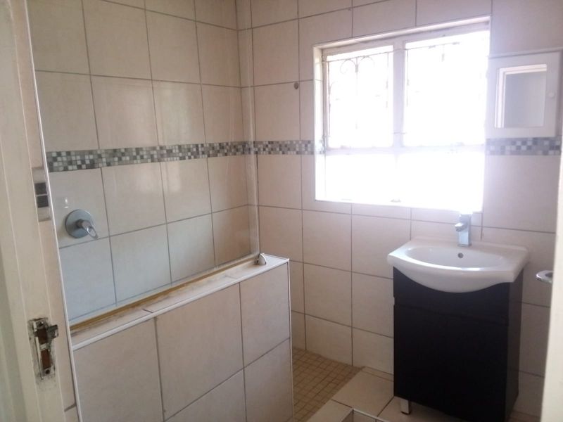 A functional bathroom featuring tiled walls, a vanity basin, and a shower area with a glass screen.