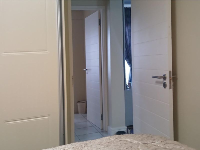 A view through a hallway featuring modern internal doors and a built-in wardrobe, leading towards an adjacent room with tiled flooring.