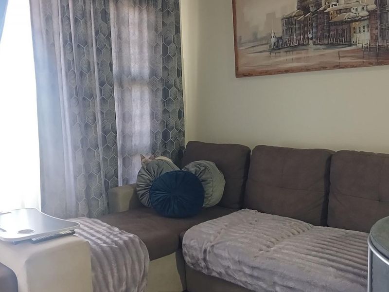 A comfortable living room area featuring natural light through window treatments, providing a functional space for relaxation.