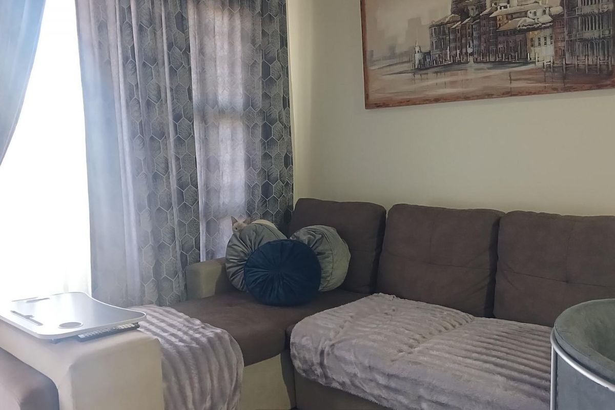 A comfortable living room area featuring natural light through window treatments, providing a functional space for relaxation.