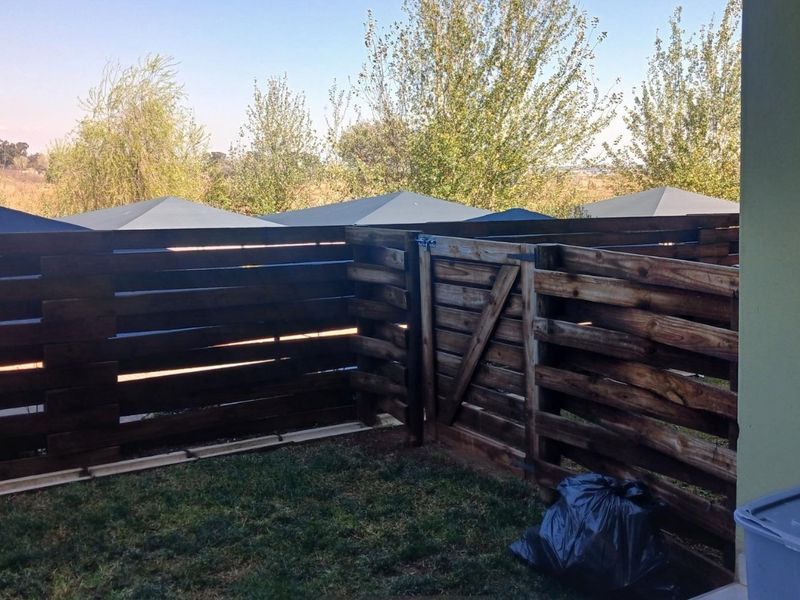 A private rear garden area featuring dark-stained timber slat fencing and a matching gate, providing a secure outdoor space.