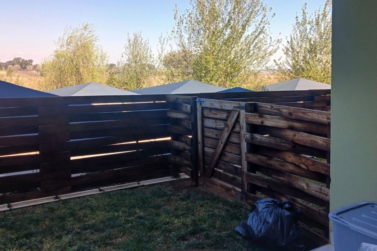 A private rear garden area featuring dark-stained timber slat fencing and a matching gate, providing a secure outdoor space.