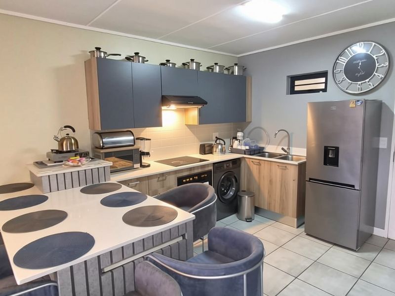 Modern open-plan kitchen featuring contemporary cabinetry, integrated appliances, and tiled flooring, seamlessly connecting to the dining area.